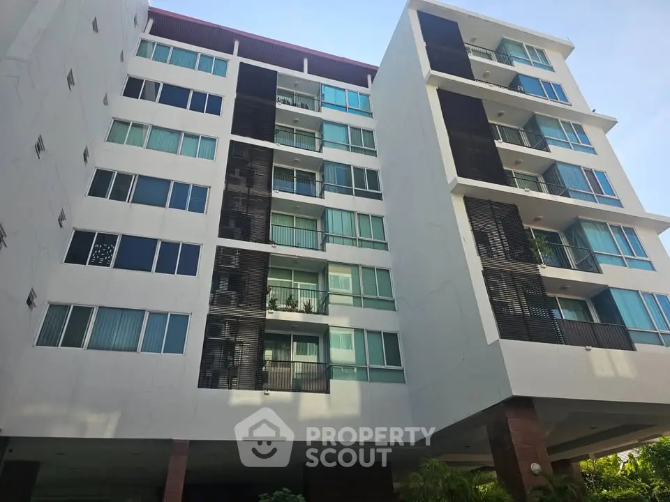 Modern multi-story apartment building with balconies and large windows.
