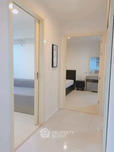 Bright hallway leading to a modern bedroom with sleek furniture and tiled flooring.