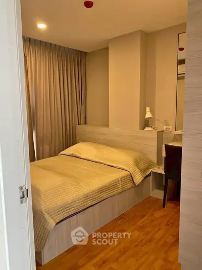 Cozy bedroom with wooden flooring and modern furnishings in a stylish apartment.