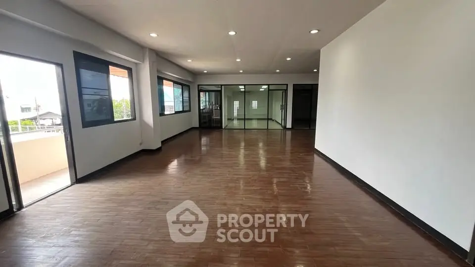 Spacious open-plan living area with wooden flooring and large windows