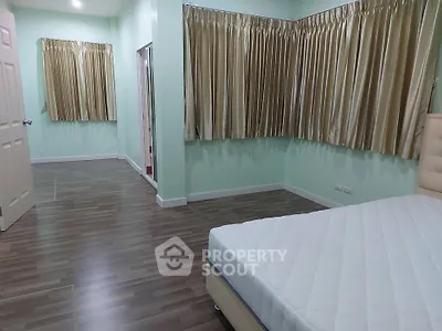 Spacious bedroom with elegant curtains and hardwood flooring