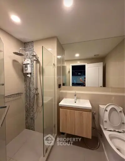 Modern bathroom with glass shower and sleek vanity in contemporary apartment.