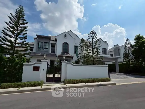 Elegant white two-story house with lush landscaping and clear blue sky.