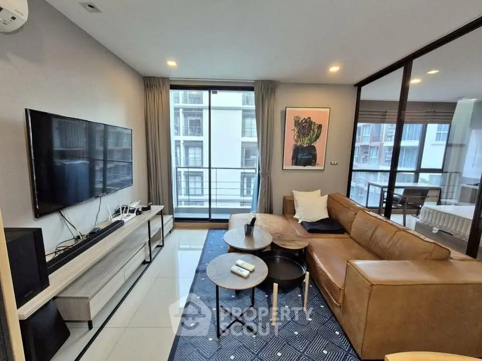 Modern living room with sleek furniture and large TV, featuring a balcony view.