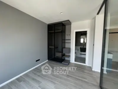 Modern bedroom with sleek glass wardrobe and en-suite bathroom in contemporary apartment