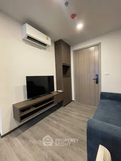 Modern living room with sleek TV setup and air conditioning in a stylish apartment.