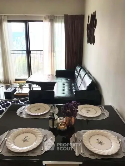 Stylish living room with elegant dining setup and modern decor, featuring a cozy sofa and large window view.