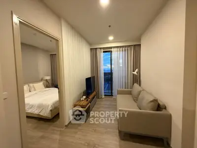 Modern apartment living room with cozy sofa and TV, adjacent to a stylish bedroom with a view.