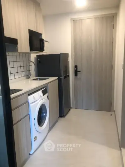 Modern compact kitchen with washing machine and fridge in sleek apartment