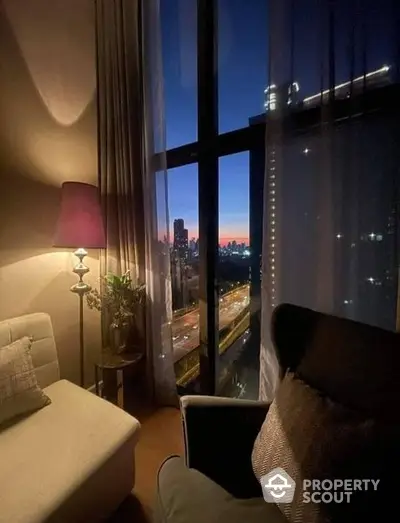 Cozy living room with plush seating and floor-to-ceiling windows offering a breathtaking city skyline view at dusk, perfect for urban living.