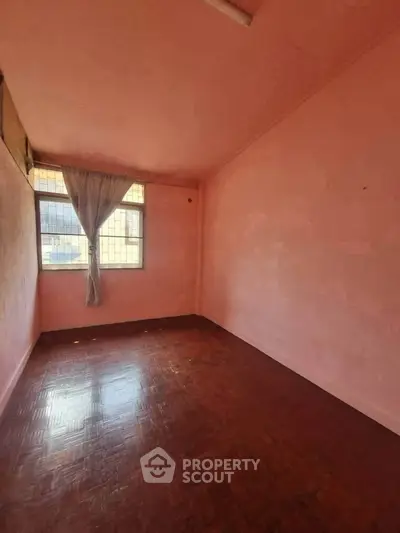 Spacious empty room with pink walls and large window, perfect for customization.