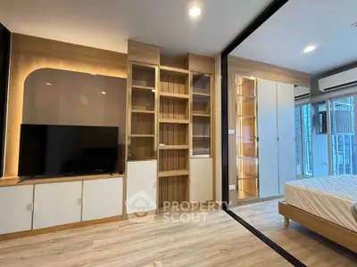 Modern bedroom with built-in storage and TV, featuring sleek design and ample natural light.