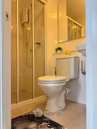 Modern bathroom with shower and toilet in a compact layout, featuring sleek white tiles and a stylish mirror.
