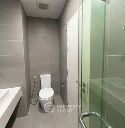 Modern bathroom with sleek gray tiles and glass shower enclosure