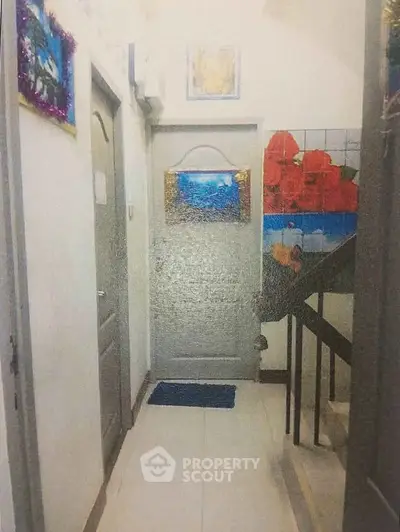 Charming hallway with artistic decor and stairway in a residential building.