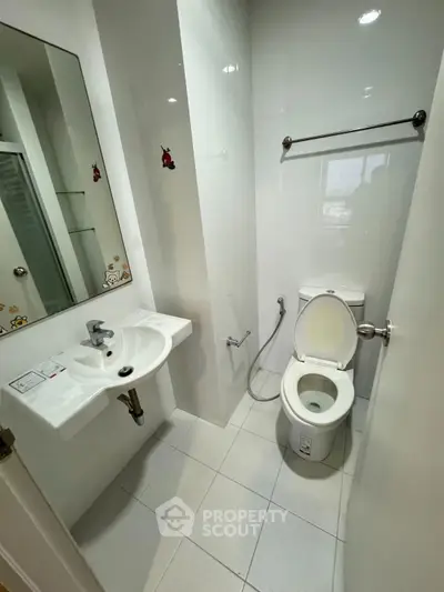 Compact modern bathroom with white fixtures and wall-mounted sink