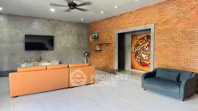 Spacious living room with modern decor, exposed brick wall, and stylish furniture.