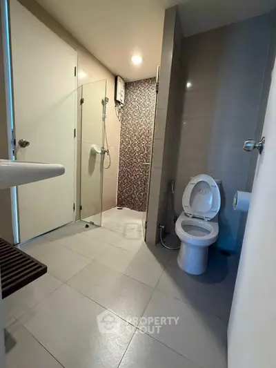 Modern bathroom with glass shower and sleek fixtures in contemporary apartment.