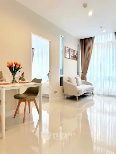 Bright and modern living room with dining area, featuring sleek furniture and large windows for natural light.