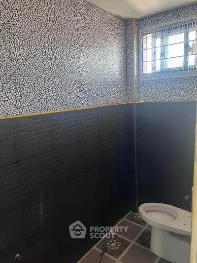 Modern bathroom with unique patterned tiles and window for natural light.