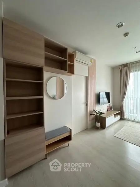 Modern living room with stylish shelving and TV setup, featuring natural light and minimalist decor.