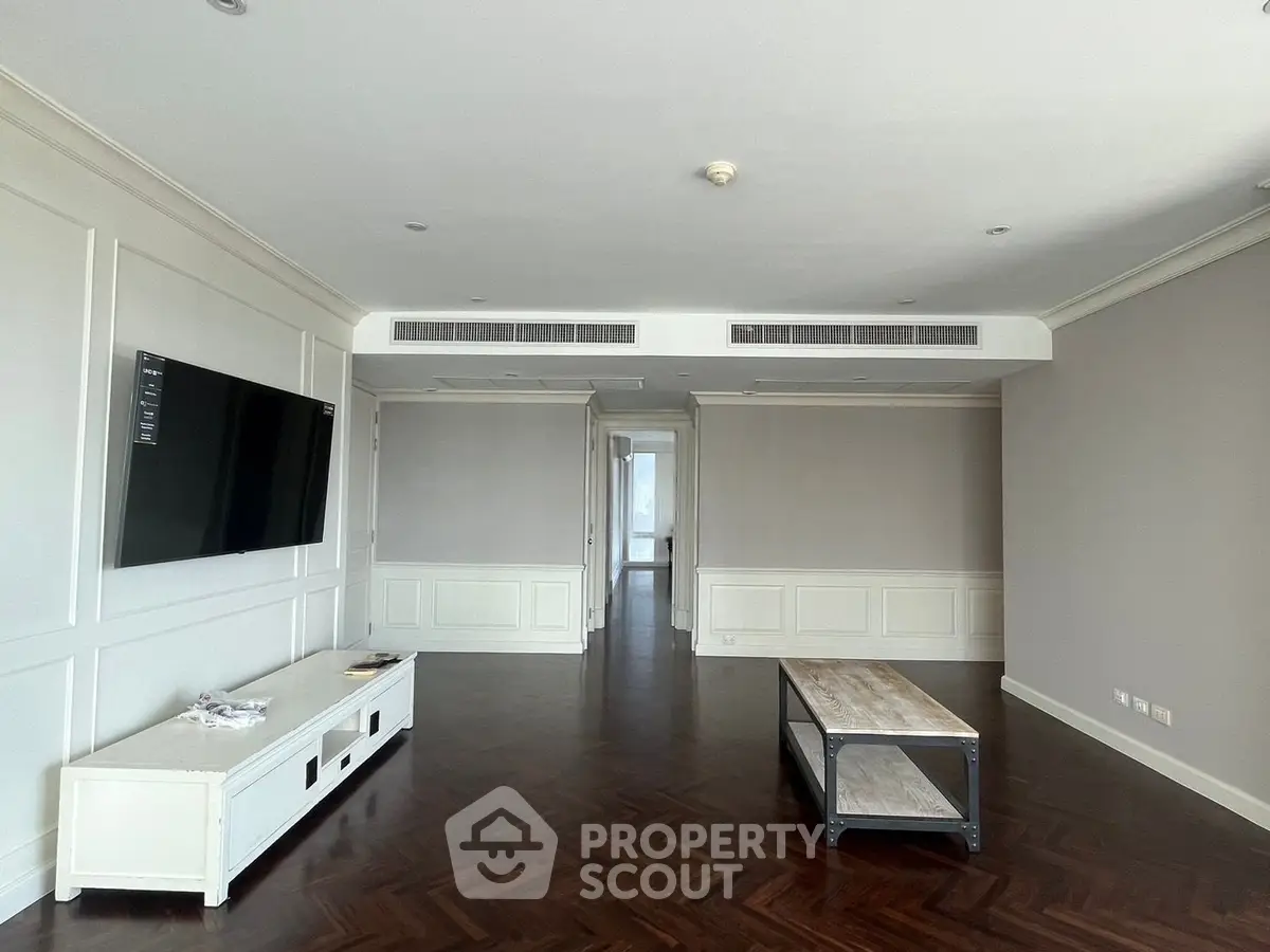 Spacious living room with elegant wood flooring and modern TV setup