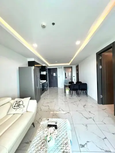 Modern open-plan living room with sleek kitchen and dining area, featuring elegant marble flooring.