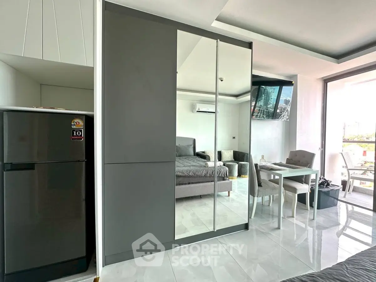 Modern studio apartment with sleek mirrored wardrobe and compact dining area.