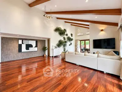 Spacious living room with high ceilings, wooden beams, and elegant decor in a modern home.