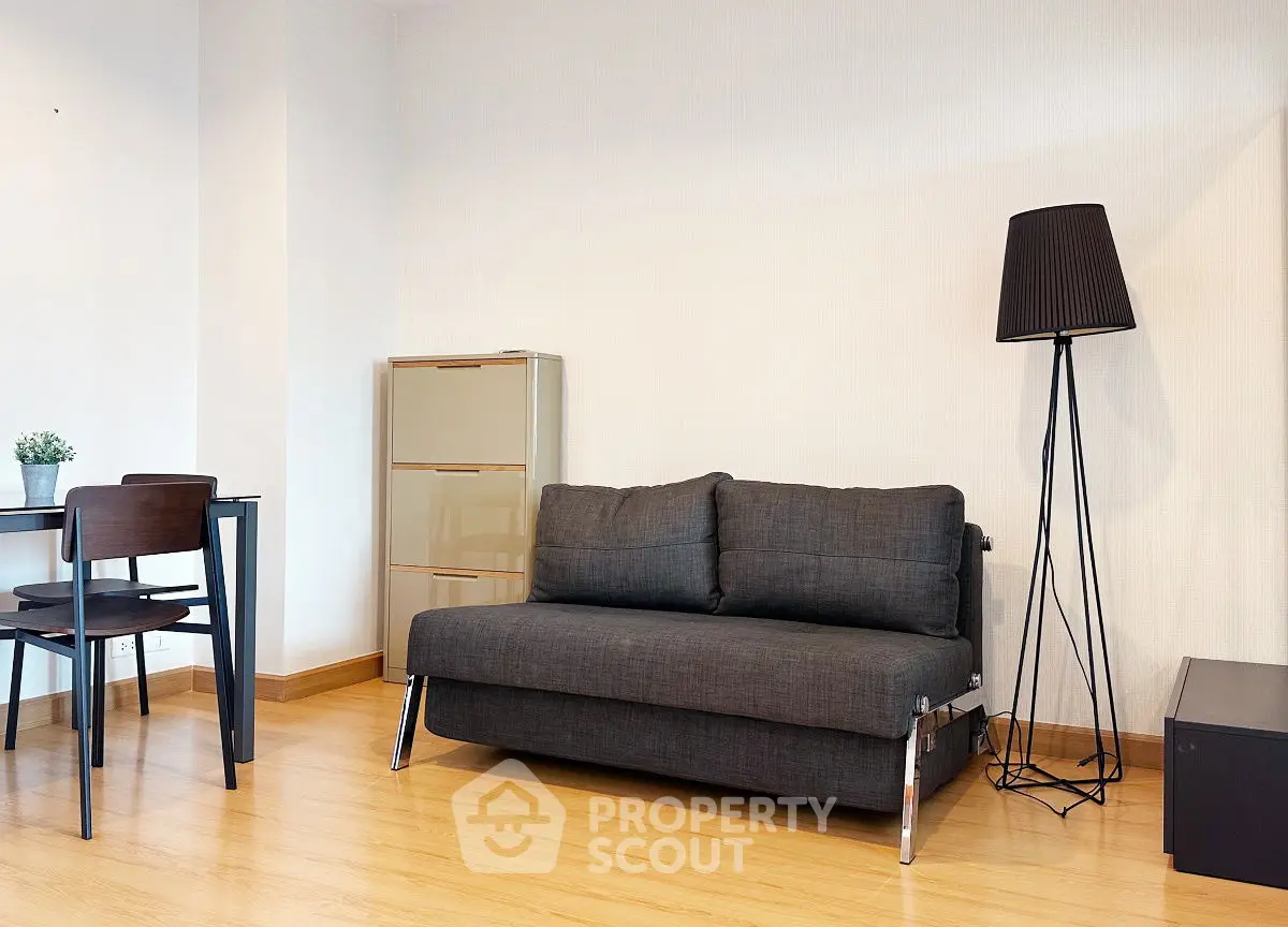 Modern living room with sleek black sofa, stylish lamp, and minimalist decor.