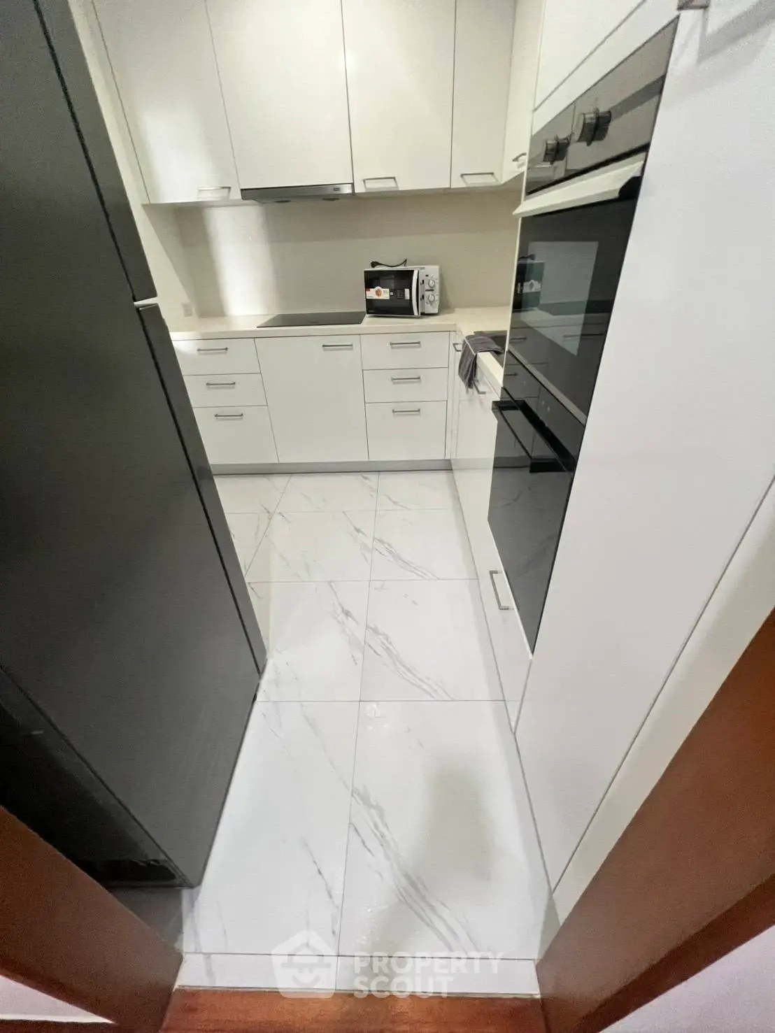 Modern kitchen with sleek cabinetry and built-in oven, featuring a compact and efficient layout.