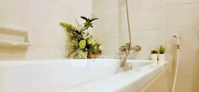 Elegant bathroom with white tiles and floral decor, featuring a sleek bathtub and modern fixtures.