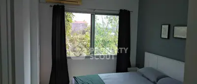 Cozy bedroom with large window and serene view of greenery.