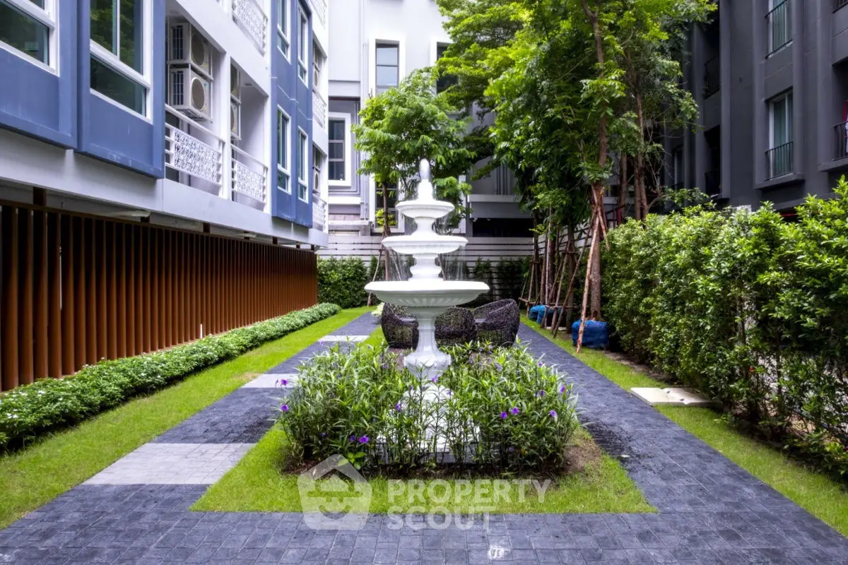 Charming garden courtyard with elegant fountain and lush greenery in modern residential complex.