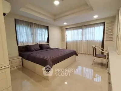 Spacious bedroom with elegant decor and large windows for natural light.