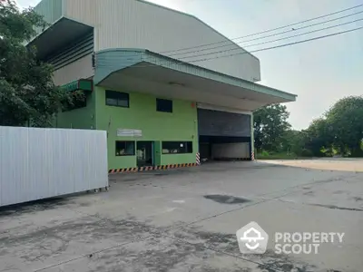 Industrial warehouse exterior with large loading bay and spacious concrete yard.