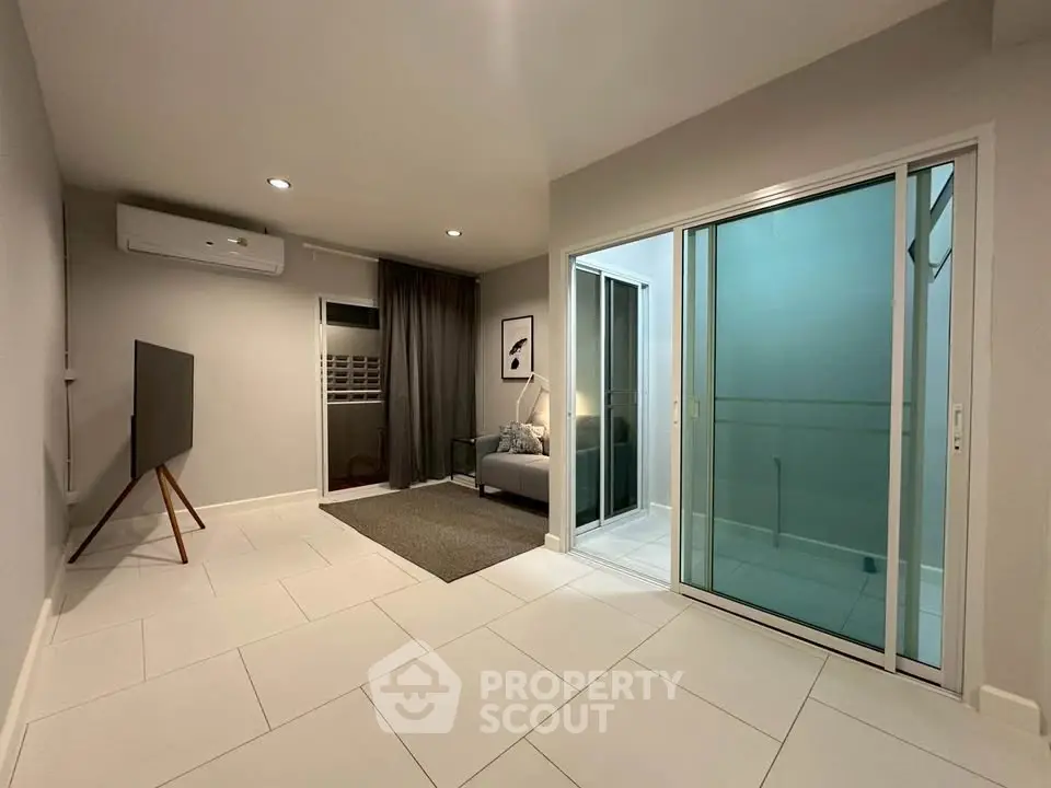 Modern living room with sleek design and sliding glass doors leading to a balcony.