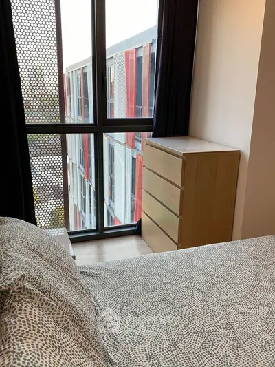 Modern bedroom with large window and dresser, offering a view of contemporary architecture.