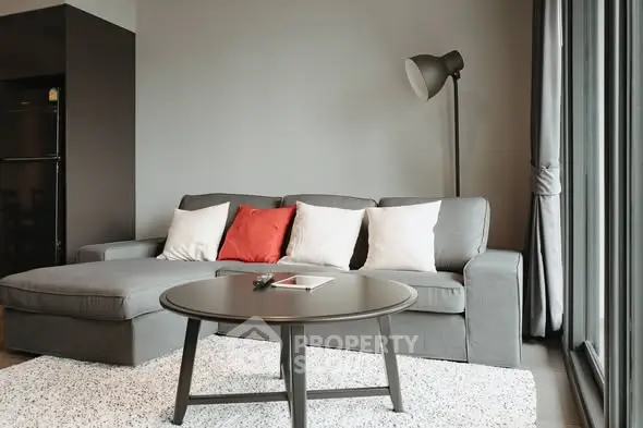 Modern living room with stylish gray sofa and floor lamp, featuring large windows for natural light.