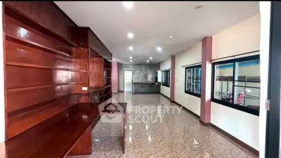 Spacious open-plan living area with wooden shelves and large windows