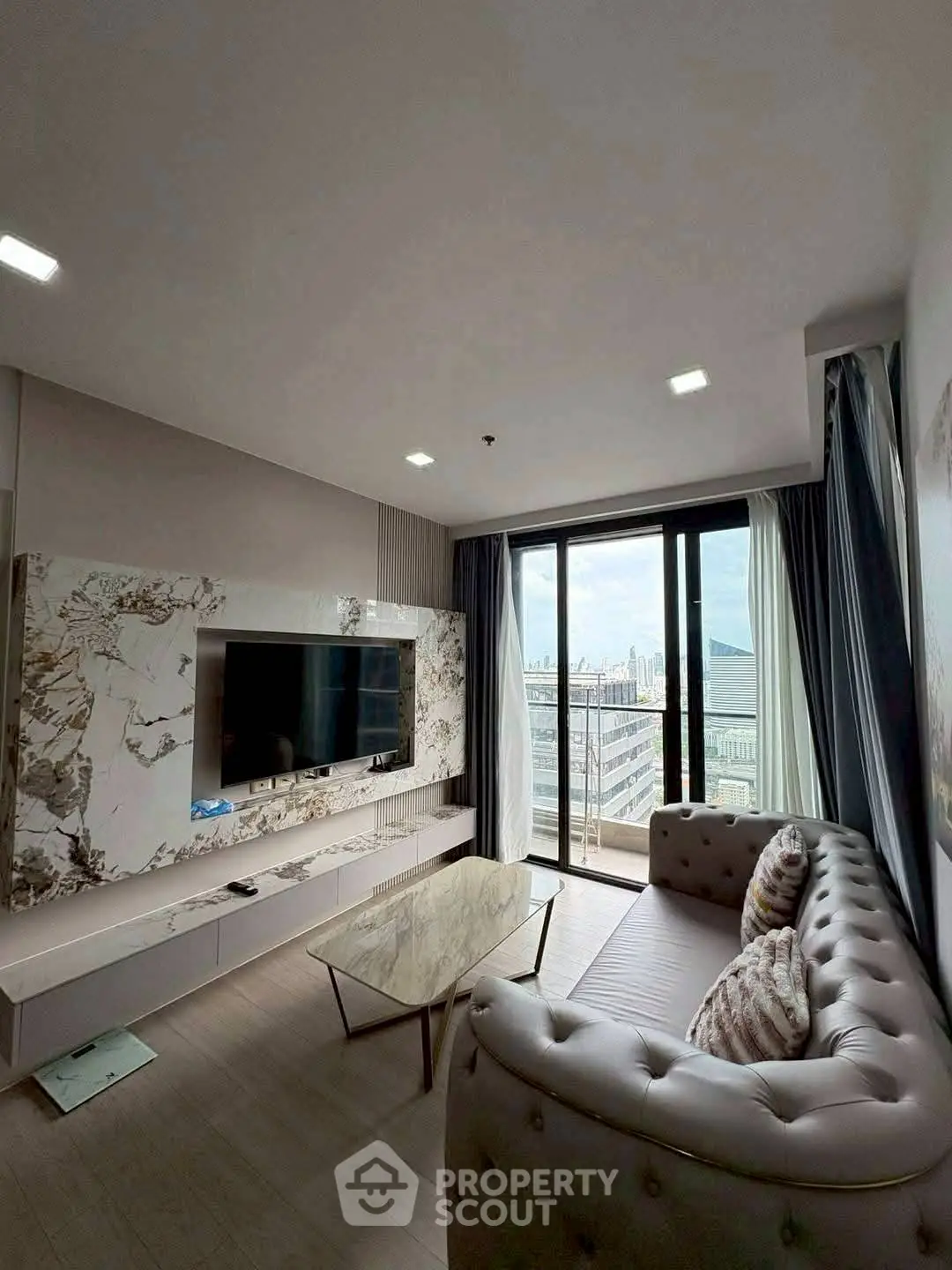Luxurious living room with modern decor and stunning city view from balcony.