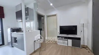 Modern living room with sleek design and open kitchen layout, featuring a TV and stylish decor.