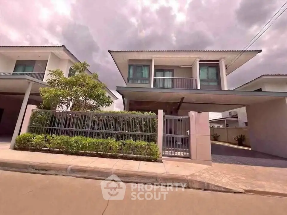 Modern two-story house with balcony and gated entrance in a suburban neighborhood.