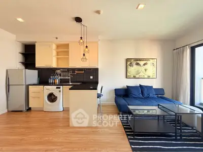 Modern open-plan living room with kitchen, featuring stylish decor and natural light.