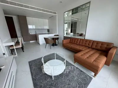 Modern open-layout living room with stylish brown sofa and sleek kitchen area.