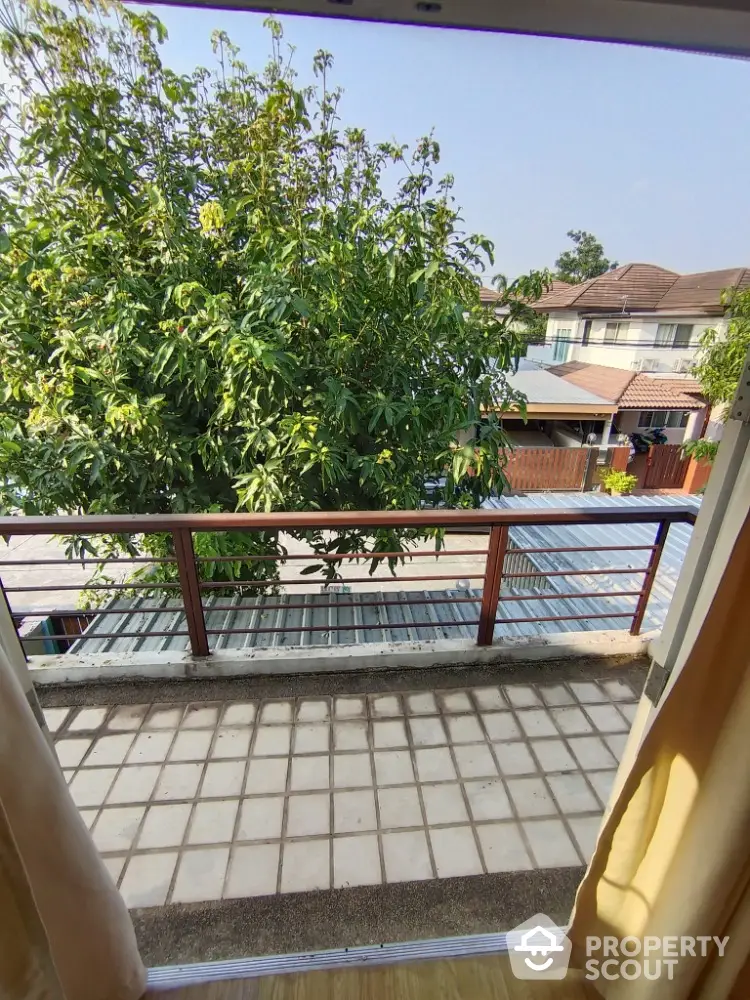 Charming balcony with a lush green view, offering a serene outdoor space for relaxation in a residential neighborhood.