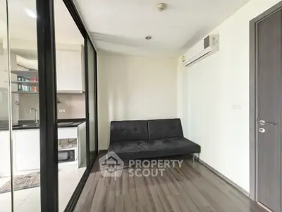 Modern compact living room with sleek black sofa and glass partition