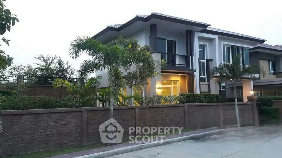 Modern two-story house with lush garden and palm trees, showcasing elegant architecture and spacious outdoor area.
