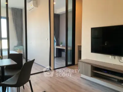 Modern living room with sleek design and large TV, adjacent to a stylish bedroom.
