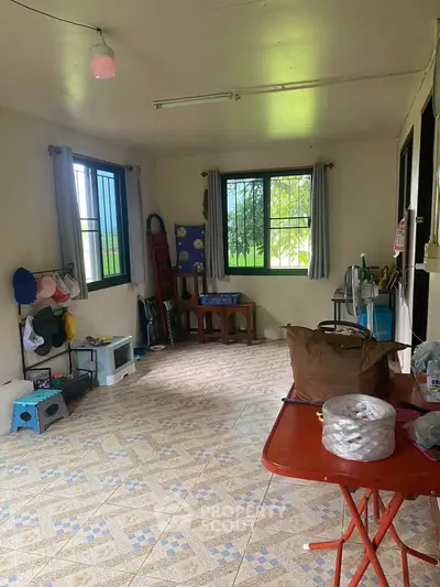 Spacious room with tiled flooring and large windows, ideal for versatile use in a cozy home.